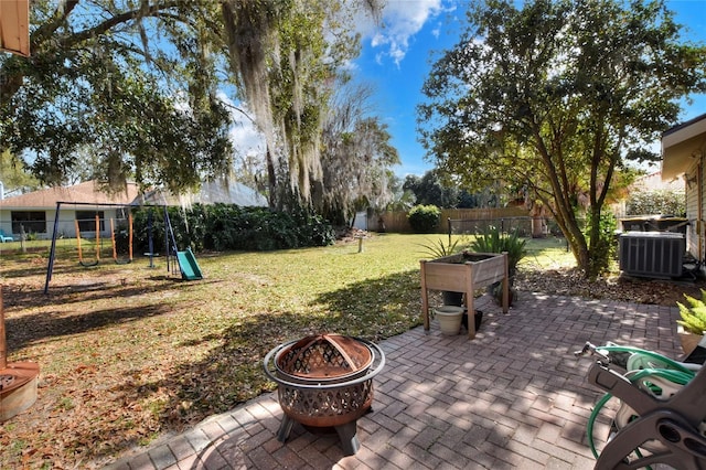 view of yard featuring a fire pit, central air condition unit, a patio area, and a playground