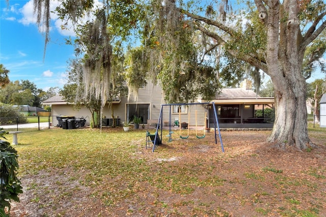 back of property with a playground, a sunroom, a yard, and central AC