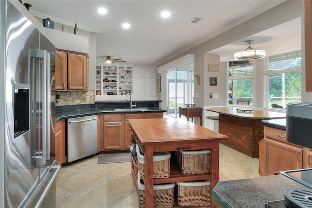 kitchen with a healthy amount of sunlight, ornamental molding, stainless steel appliances, and light tile patterned floors