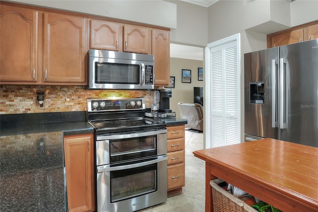 kitchen featuring light tile patterned flooring, appliances with stainless steel finishes, crown molding, and backsplash