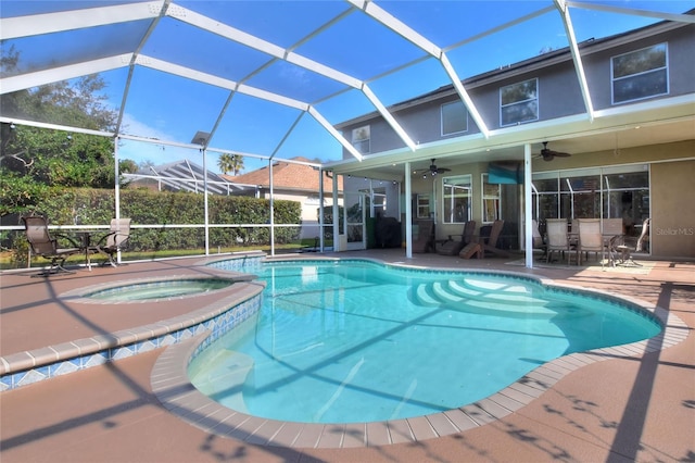 view of pool with an in ground hot tub, a patio area, ceiling fan, and glass enclosure