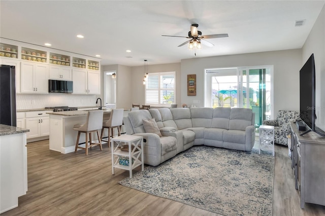 living room with a wealth of natural light, sink, ceiling fan, and wood-type flooring