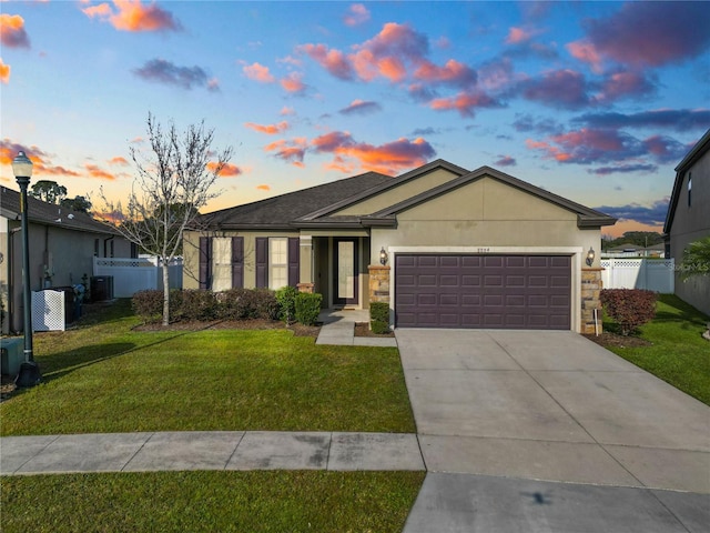 ranch-style home featuring a garage, central air condition unit, and a lawn