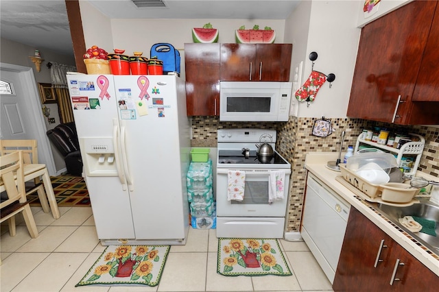 kitchen with light tile patterned flooring, white appliances, and backsplash