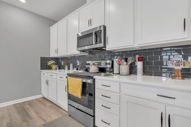 kitchen with appliances with stainless steel finishes, light hardwood / wood-style flooring, white cabinetry, and tasteful backsplash