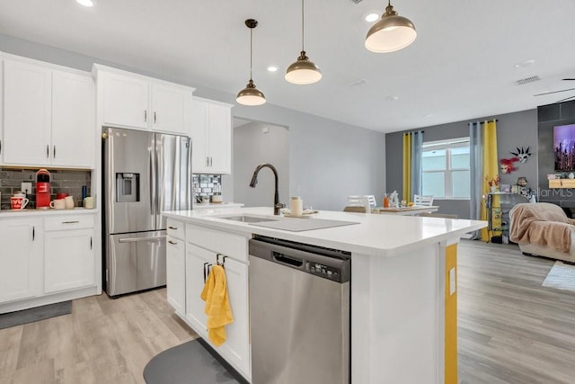 kitchen with sink, white cabinetry, stainless steel appliances, and a kitchen island with sink