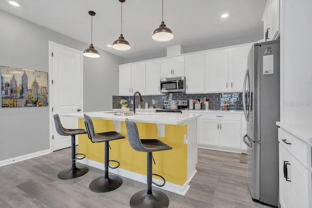 kitchen with white cabinetry, an island with sink, stainless steel appliances, pendant lighting, and a breakfast bar