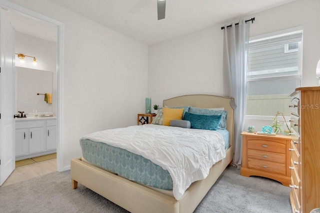 bedroom with ceiling fan, light colored carpet, and ensuite bathroom