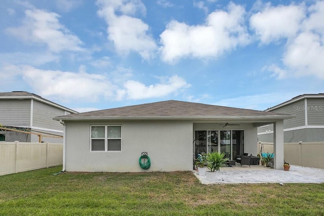 rear view of property with ceiling fan, a yard, and a patio