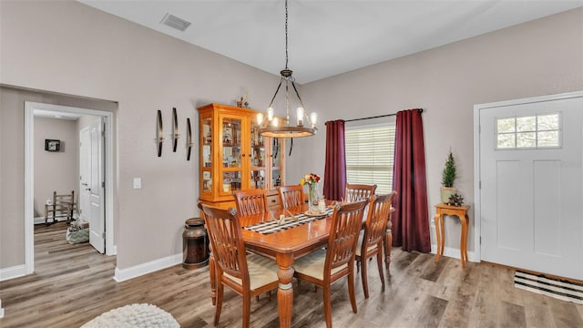 dining room featuring light wood-type flooring and an inviting chandelier