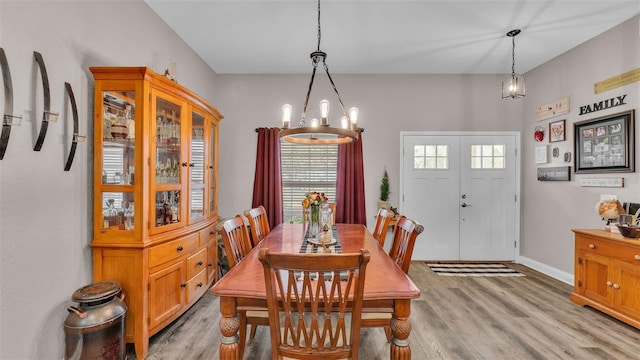 dining space with light hardwood / wood-style floors and a notable chandelier