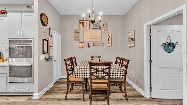 dining area featuring light hardwood / wood-style floors and an inviting chandelier