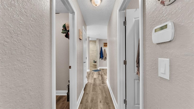 corridor with hardwood / wood-style flooring and a textured ceiling