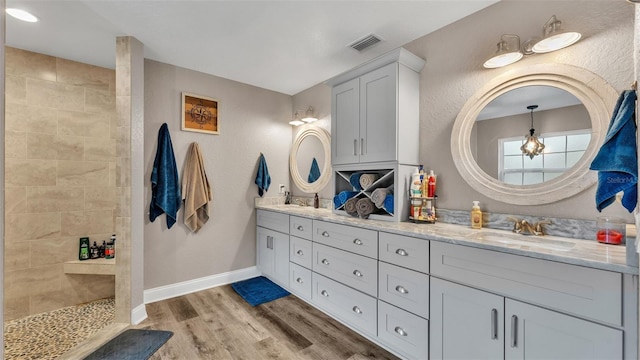 bathroom with hardwood / wood-style floors, vanity, and a tile shower