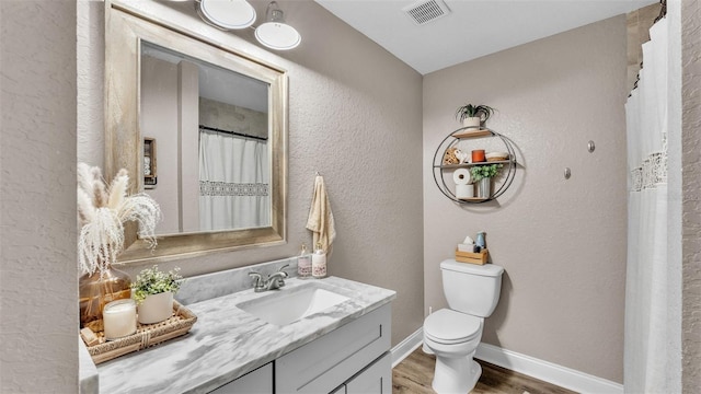 bathroom featuring vanity, wood-type flooring, and toilet