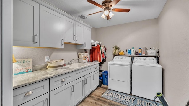 laundry area featuring cabinets, light wood-type flooring, ceiling fan, sink, and independent washer and dryer