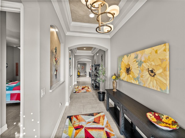 hall featuring a tray ceiling, crown molding, a chandelier, and light tile patterned floors