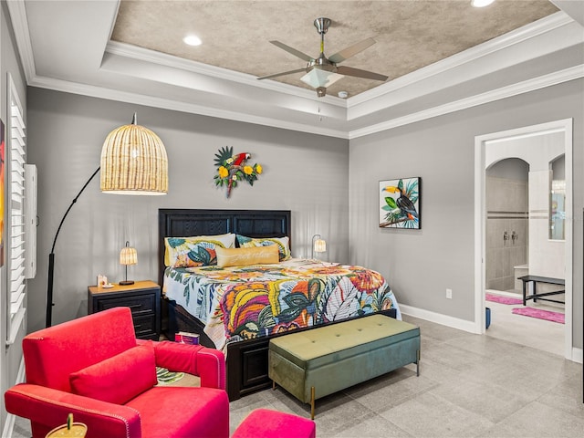 bedroom with ornamental molding, ceiling fan, connected bathroom, and a tray ceiling