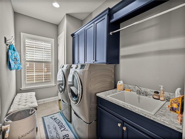 clothes washing area featuring light tile patterned floors, washing machine and dryer, cabinets, and sink