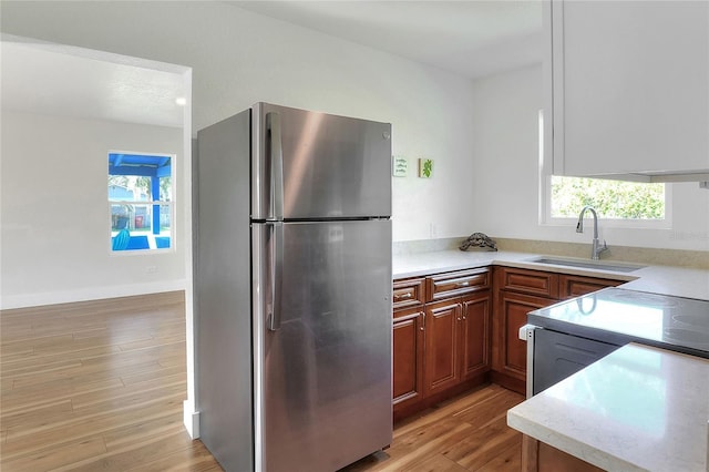 kitchen featuring stainless steel refrigerator, sink, and light wood-type flooring