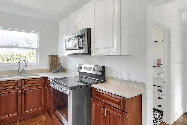 kitchen featuring hardwood / wood-style flooring, sink, white cabinets, and appliances with stainless steel finishes