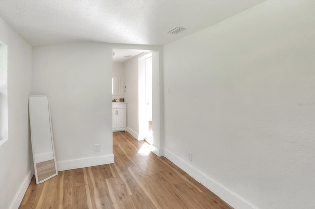 unfurnished room featuring light hardwood / wood-style flooring and a textured ceiling