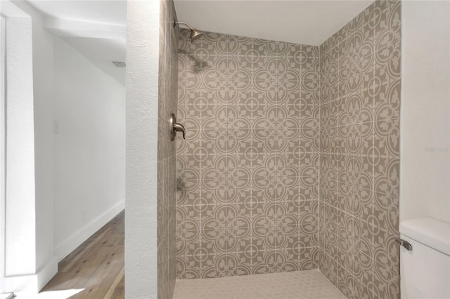 bathroom featuring tiled shower, hardwood / wood-style flooring, and toilet