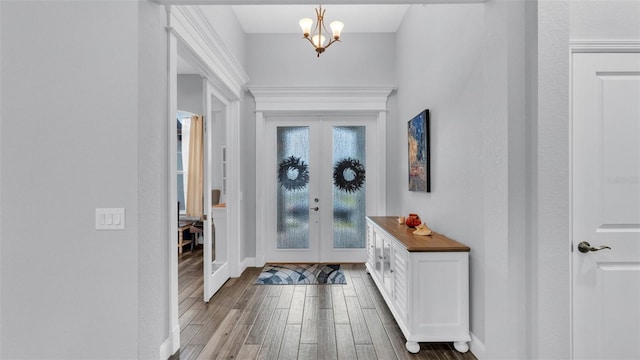 entrance foyer with french doors, a chandelier, and hardwood / wood-style flooring