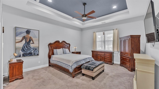 carpeted bedroom featuring ceiling fan and a tray ceiling