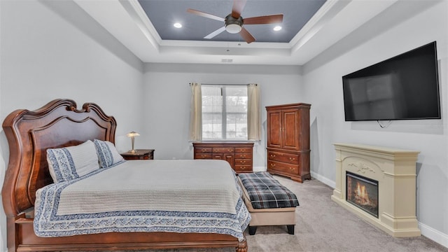 carpeted bedroom featuring ceiling fan and a tray ceiling