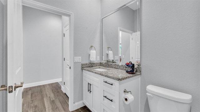 bathroom with toilet, vanity, and hardwood / wood-style flooring