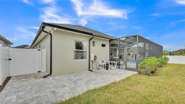 back of house with a patio, glass enclosure, and a yard