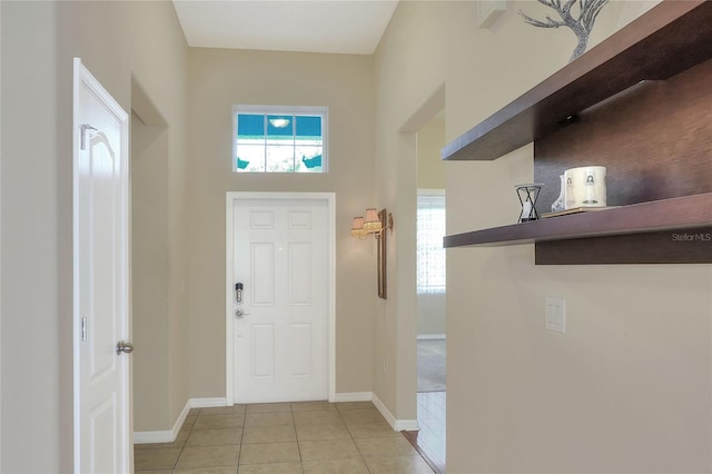 entryway with light tile patterned floors, a wealth of natural light, and a high ceiling