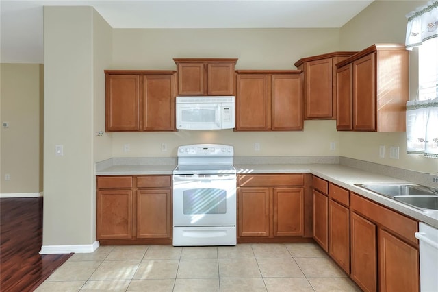 kitchen featuring white appliances, sink, and light tile patterned floors