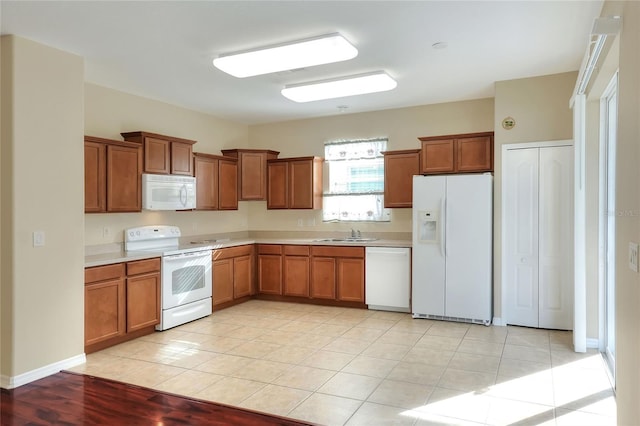 kitchen featuring sink, light tile patterned floors, and white appliances