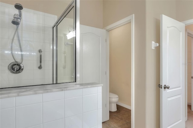 bathroom featuring tile patterned floors, toilet, and tiled shower