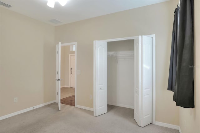 unfurnished bedroom featuring light carpet and a closet