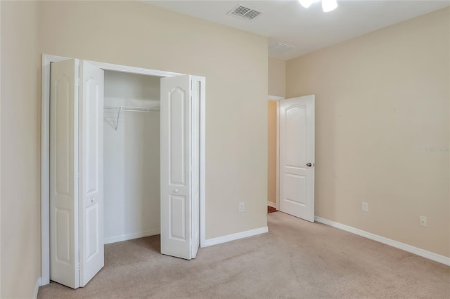 unfurnished bedroom with light colored carpet and a closet