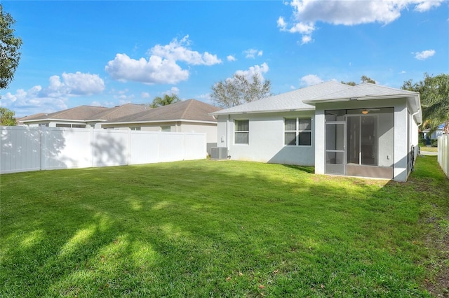 rear view of house with a sunroom, central AC unit, and a lawn