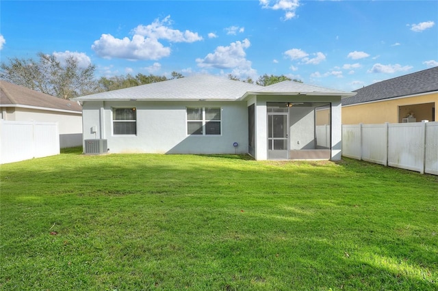 rear view of property with a lawn, central air condition unit, and a sunroom