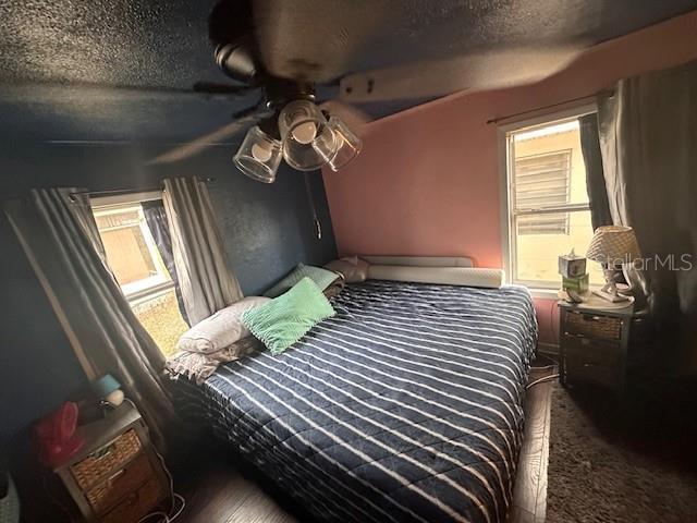 bedroom with multiple windows, ceiling fan, and a textured ceiling