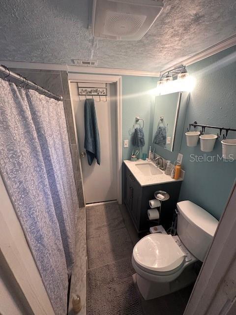 bathroom with vanity, toilet, a shower with shower curtain, and a textured ceiling