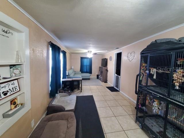 living room with light tile patterned floors, crown molding, and built in shelves