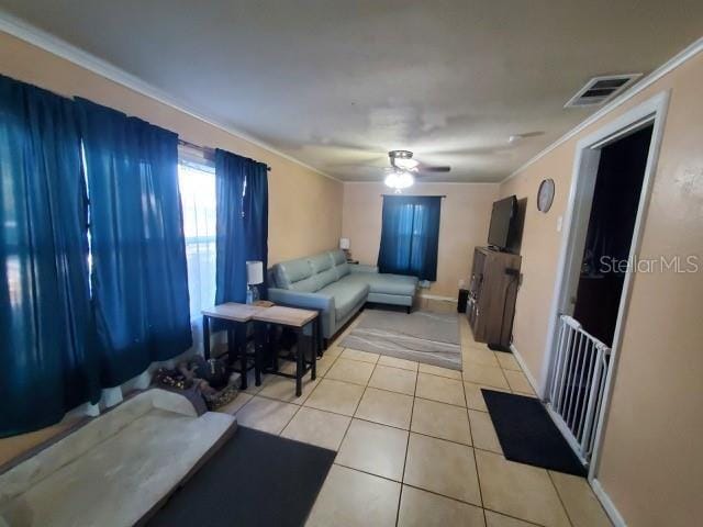 tiled living room with ornamental molding and ceiling fan