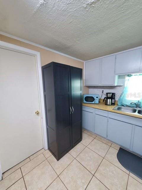 kitchen featuring sink, light tile patterned floors, and a textured ceiling