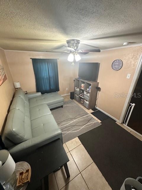 living room with a textured ceiling, ceiling fan, and light tile patterned flooring