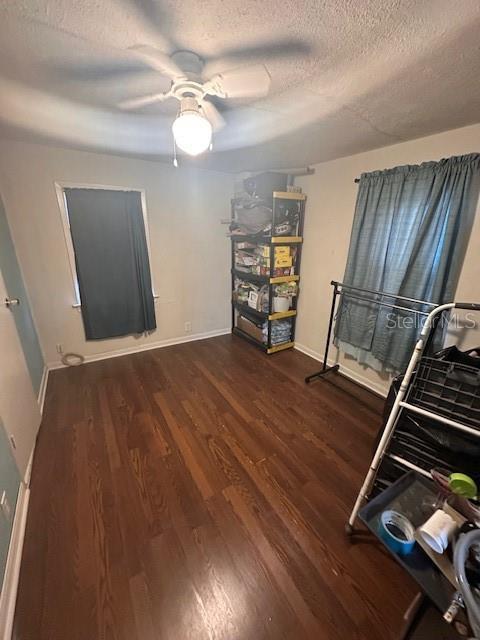 bedroom with ceiling fan, dark hardwood / wood-style floors, and a textured ceiling