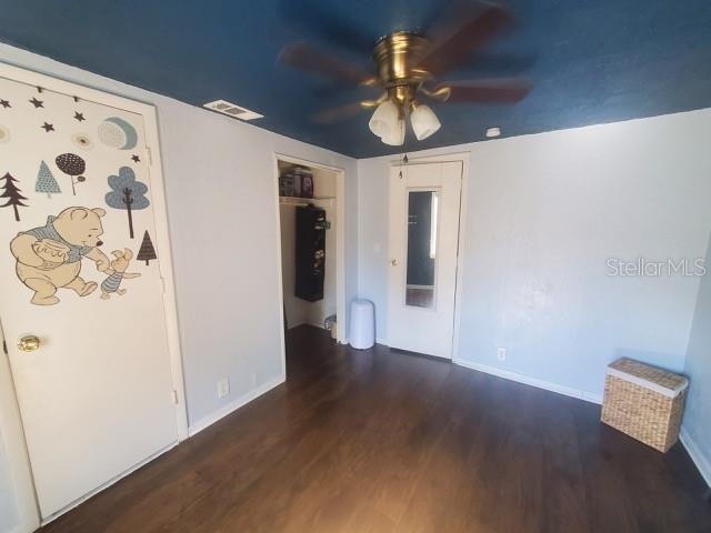 unfurnished room featuring dark wood-type flooring and ceiling fan