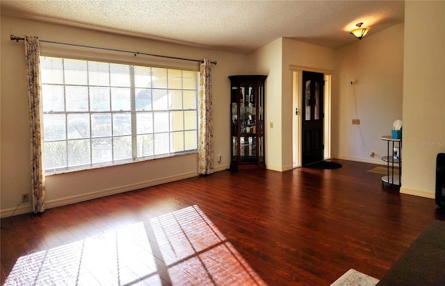 spare room featuring plenty of natural light, dark hardwood / wood-style floors, and a textured ceiling