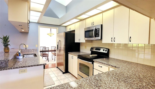 kitchen featuring decorative backsplash, dark stone counters, stainless steel appliances, sink, and light tile patterned floors